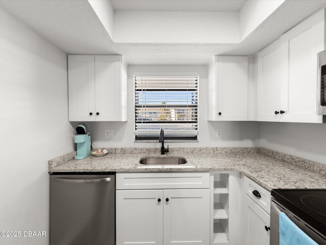 kitchen with sink, a textured ceiling, appliances with stainless steel finishes, light stone countertops, and white cabinets