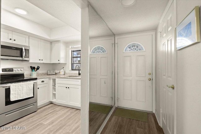 kitchen with white cabinetry, sink, light wood-type flooring, and appliances with stainless steel finishes