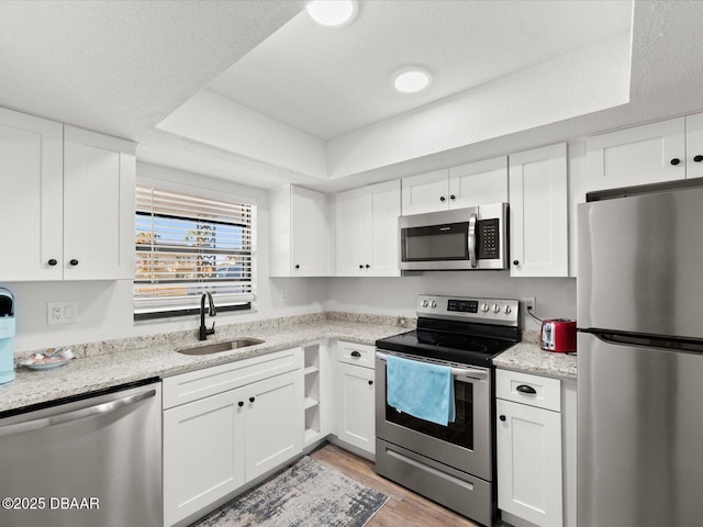 kitchen featuring white cabinetry, stainless steel appliances, a raised ceiling, and sink