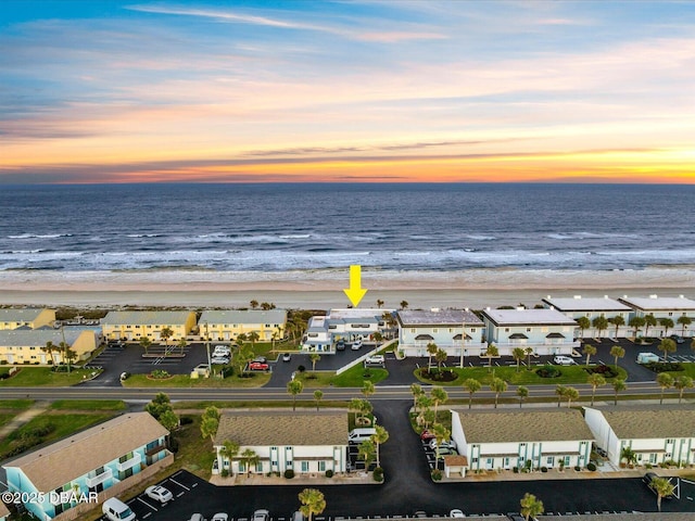 aerial view at dusk with a water view and a beach view