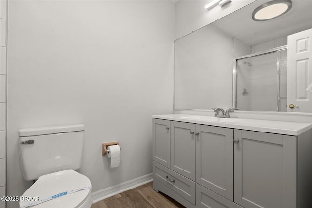 bathroom with vanity, hardwood / wood-style floors, a shower with shower door, and toilet