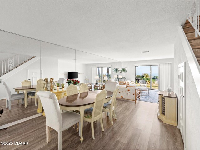 dining room with hardwood / wood-style flooring, a wealth of natural light, and a textured ceiling