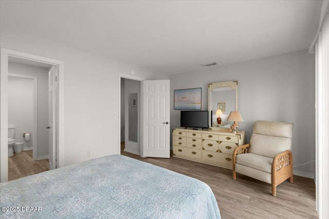 bedroom with ensuite bathroom and light wood-type flooring