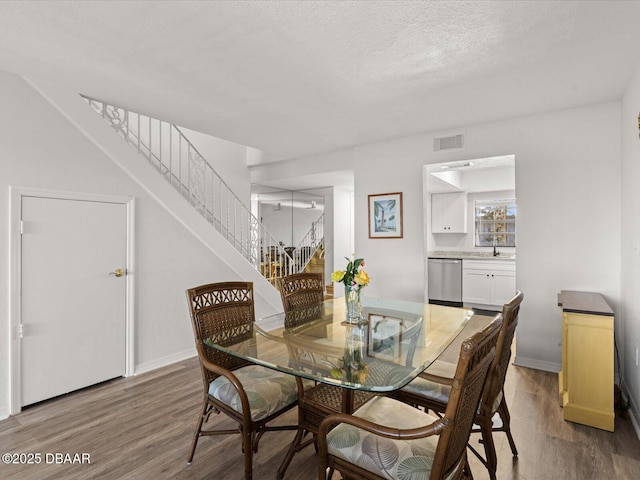 dining area featuring sink, hardwood / wood-style floors, and a textured ceiling