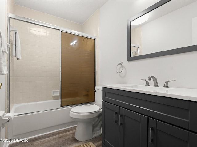 full bathroom with enclosed tub / shower combo, hardwood / wood-style floors, vanity, and toilet