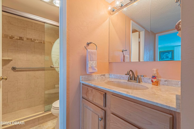 bathroom featuring vanity, a textured ceiling, toilet, and a shower with shower door