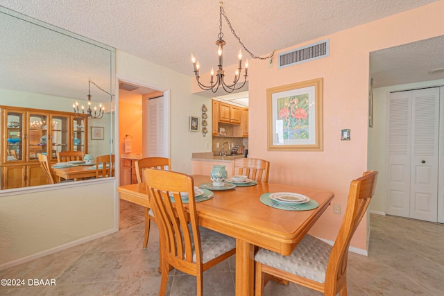 dining area with sink, a textured ceiling, a notable chandelier, and light tile patterned flooring