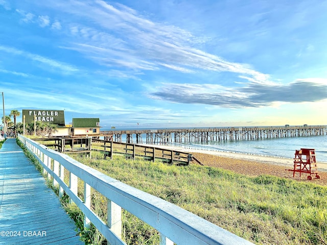 view of dock with a water view and a beach view