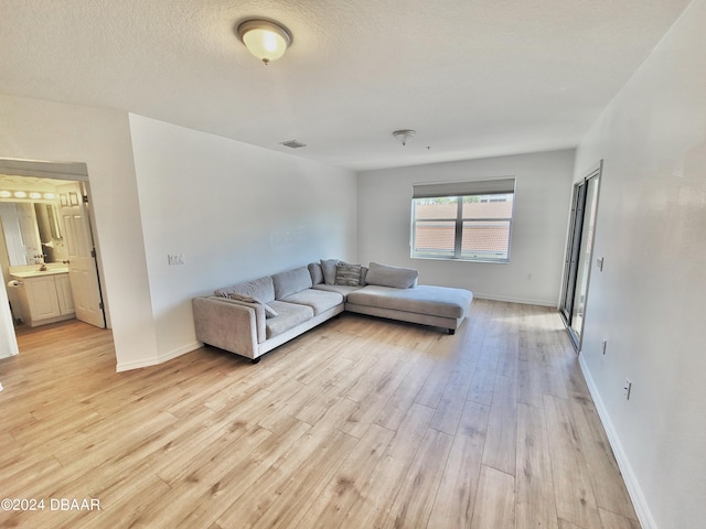 unfurnished living room featuring sink, light hardwood / wood-style flooring, and a textured ceiling