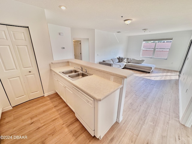 kitchen with white dishwasher, sink, kitchen peninsula, and light wood-type flooring