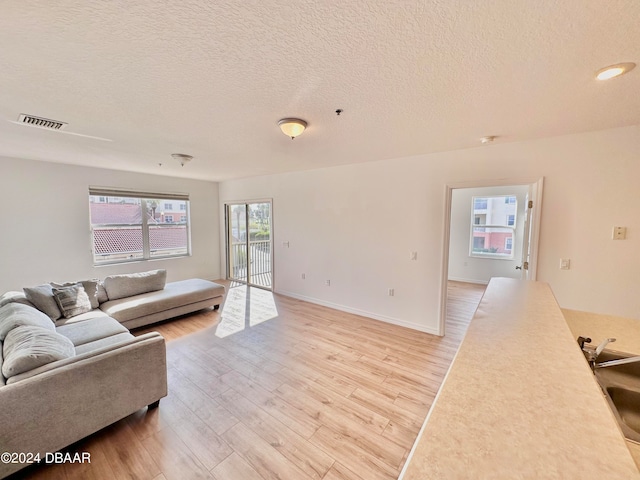 living room featuring sink, a textured ceiling, and light wood-type flooring