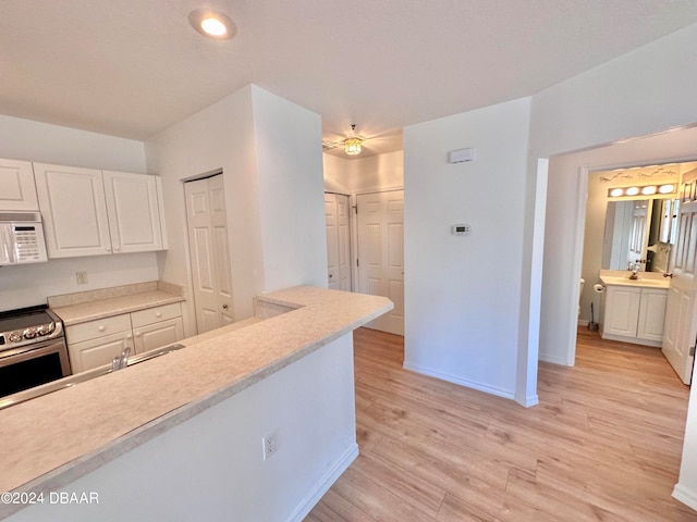 kitchen featuring stainless steel electric range oven, white cabinets, and light wood-type flooring