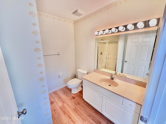 bathroom featuring vanity, hardwood / wood-style flooring, a shower with door, and toilet