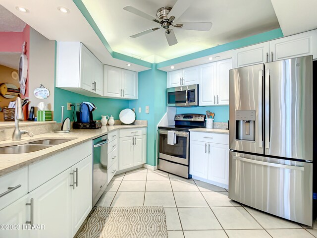 kitchen with stainless steel appliances, white cabinetry, sink, and light tile patterned floors