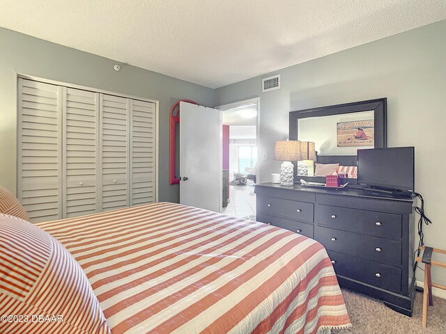 carpeted bedroom with a textured ceiling and a closet