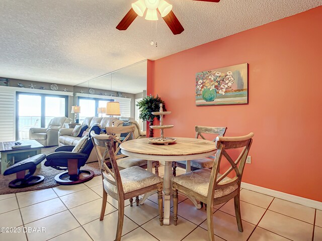 tiled dining area with ceiling fan and a textured ceiling