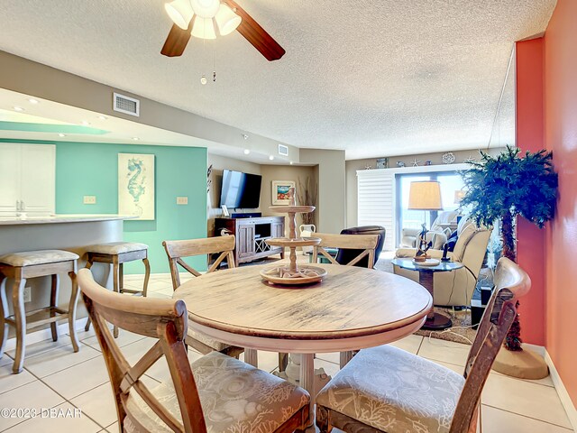 tiled dining room with a textured ceiling and ceiling fan