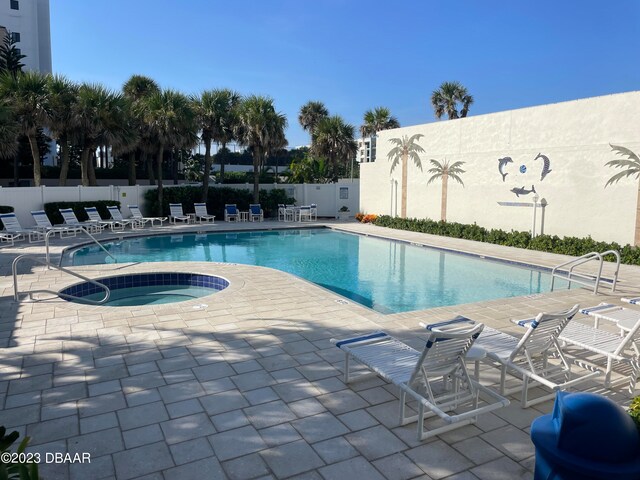 view of swimming pool featuring a patio and a hot tub