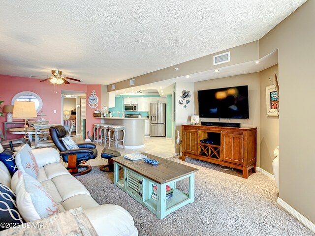 living room featuring sink, a textured ceiling, light colored carpet, and ceiling fan