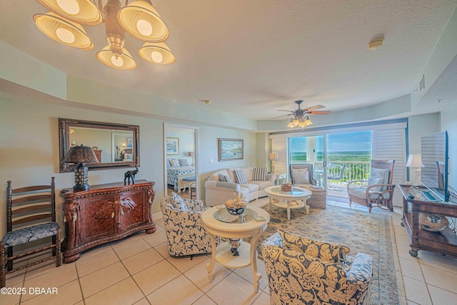 living area with a ceiling fan, a textured ceiling, and light tile patterned floors