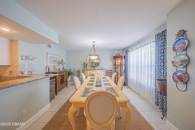 dining room with a textured ceiling, wine cooler, light tile patterned flooring, and visible vents