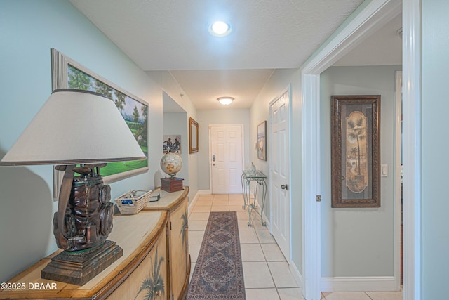 hall featuring baseboards and light tile patterned floors