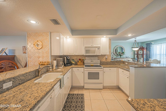 kitchen featuring light tile patterned flooring, a peninsula, white appliances, a sink, and visible vents