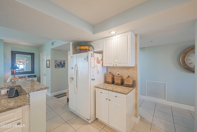 kitchen featuring white fridge with ice dispenser, visible vents, decorative backsplash, and light tile patterned flooring