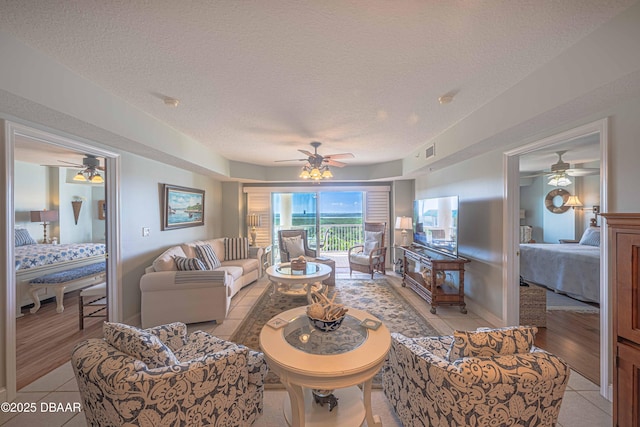 living room featuring visible vents, a textured ceiling, and light tile patterned flooring