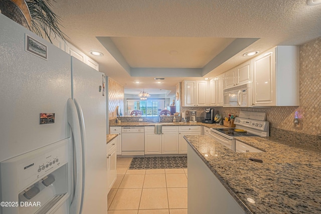 kitchen featuring white appliances, light tile patterned floors, a raised ceiling, backsplash, and a sink