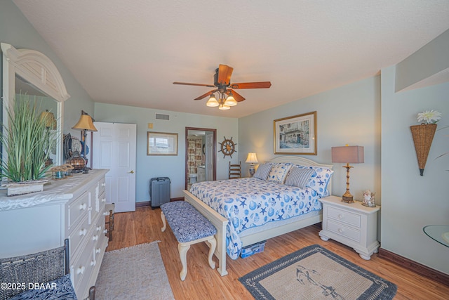 bedroom featuring baseboards, visible vents, a ceiling fan, radiator, and light wood-style floors