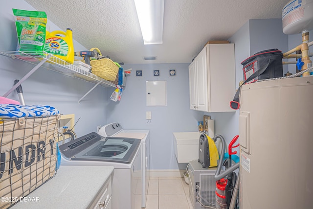 clothes washing area with light tile patterned floors, a textured ceiling, washer and dryer, electric panel, and cabinet space