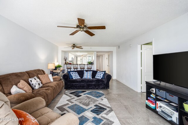 living room featuring ceiling fan and a textured ceiling