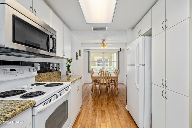 kitchen featuring white cabinets, light hardwood / wood-style flooring, light stone counters, and white appliances