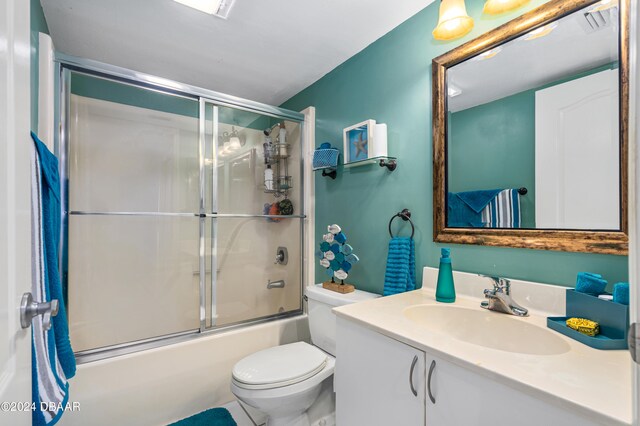 full bathroom with toilet, vanity, bath / shower combo with glass door, and tile patterned floors