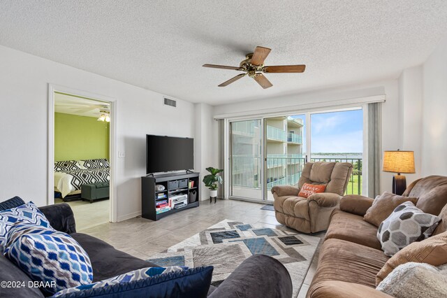 living room with light tile patterned flooring, a textured ceiling, and ceiling fan