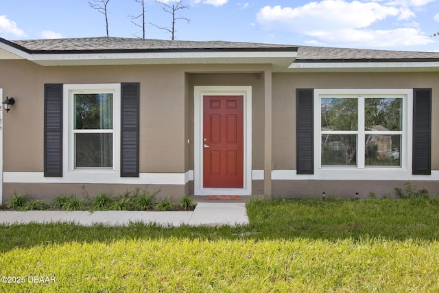 view of exterior entry featuring a lawn