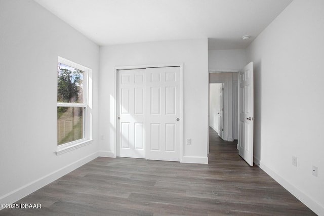 unfurnished bedroom with dark hardwood / wood-style flooring and a closet