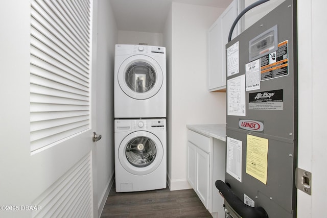 washroom with dark hardwood / wood-style floors, cabinets, stacked washing maching and dryer, and heating unit