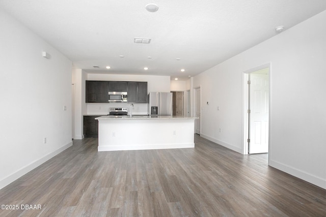 kitchen with dark hardwood / wood-style flooring, sink, a center island with sink, and appliances with stainless steel finishes