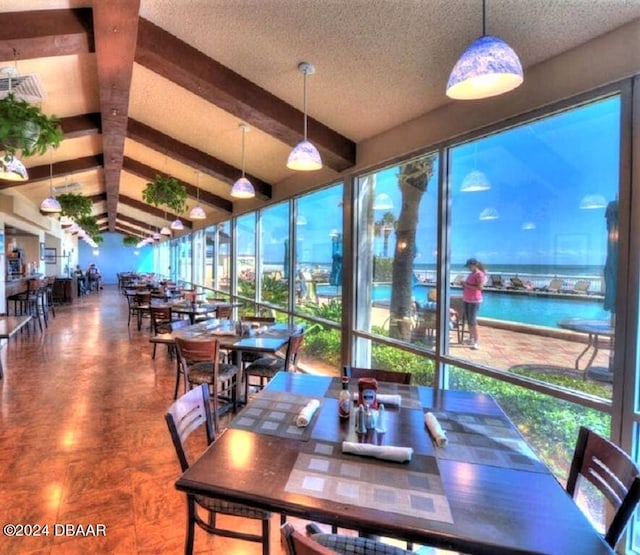 dining area with a water view and lofted ceiling with beams