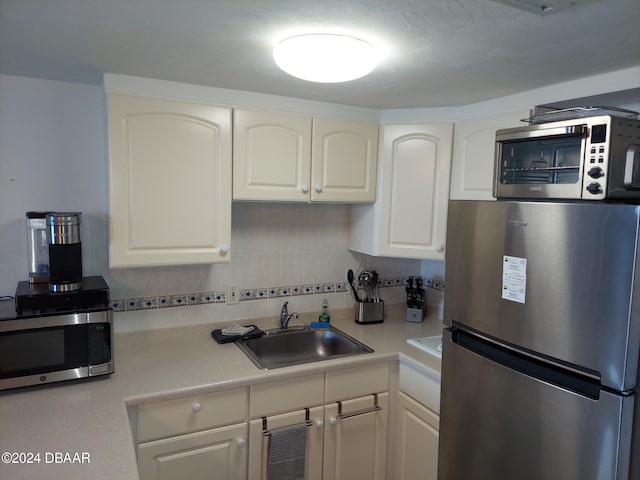 kitchen with white cabinets, decorative backsplash, appliances with stainless steel finishes, and sink