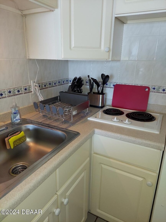 kitchen featuring white cabinets, white electric stovetop, sink, and backsplash