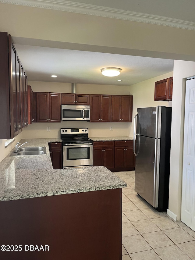 913 New Castle Ct, Holly Hill, FL 32117 - kitchen featuring appliances with stainless steel finishes, a peninsula, light tile patterned floors, dark brown cabinetry, and light stone counters