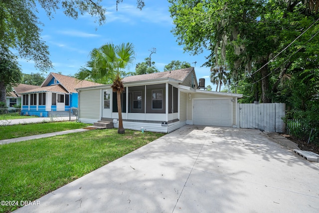 view of front of house featuring a garage, a front lawn, and a sunroom