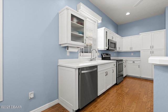3356 Newbliss Cir, Ormond Beach, FL 32174 - kitchen featuring glass insert cabinets, light countertops, appliances with stainless steel finishes, wood finished floors, and white cabinets