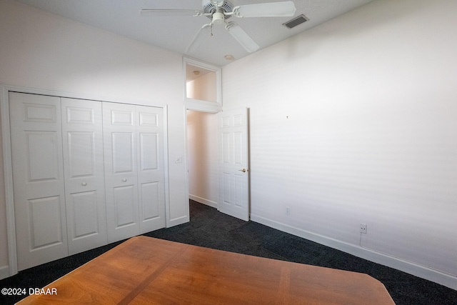 unfurnished bedroom with dark colored carpet, ceiling fan, and a closet