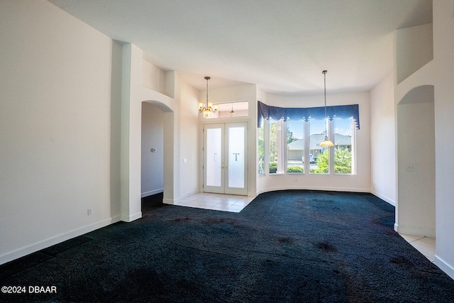 carpeted spare room with french doors and a notable chandelier