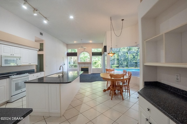 kitchen featuring white cabinetry, a fireplace, sink, and white appliances