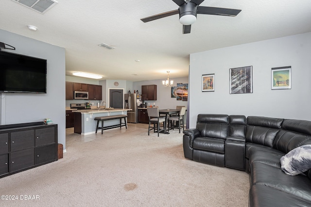 carpeted living room featuring a textured ceiling, ceiling fan with notable chandelier, and sink